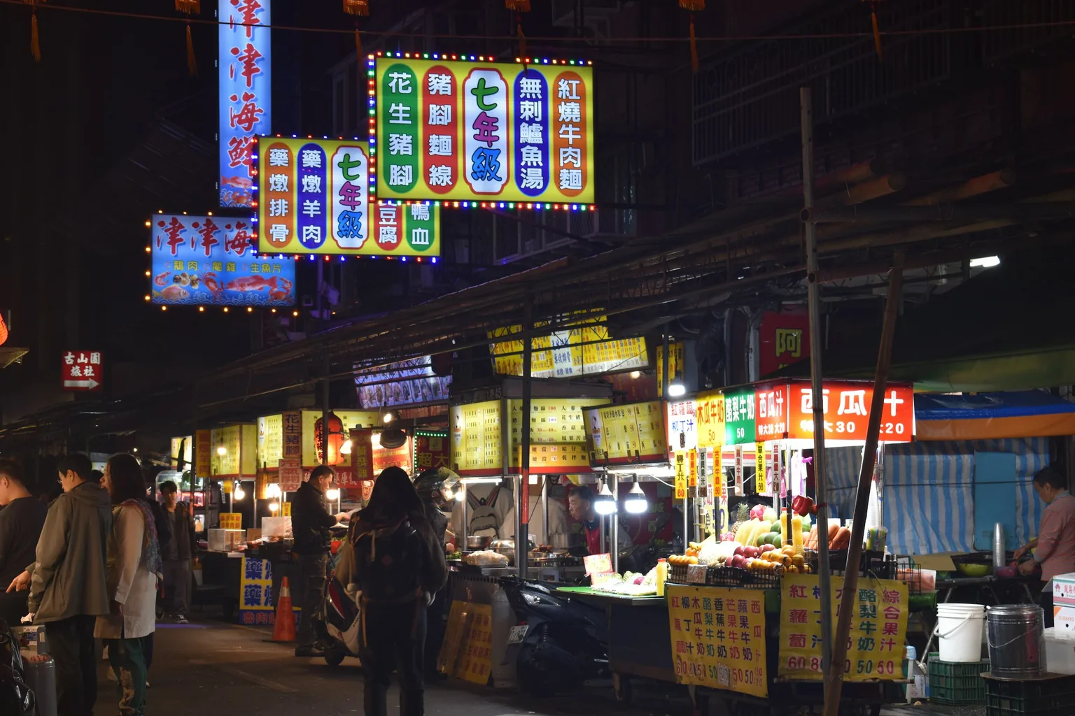 夜市裡亮著招牌燈的攤位與逛街人潮