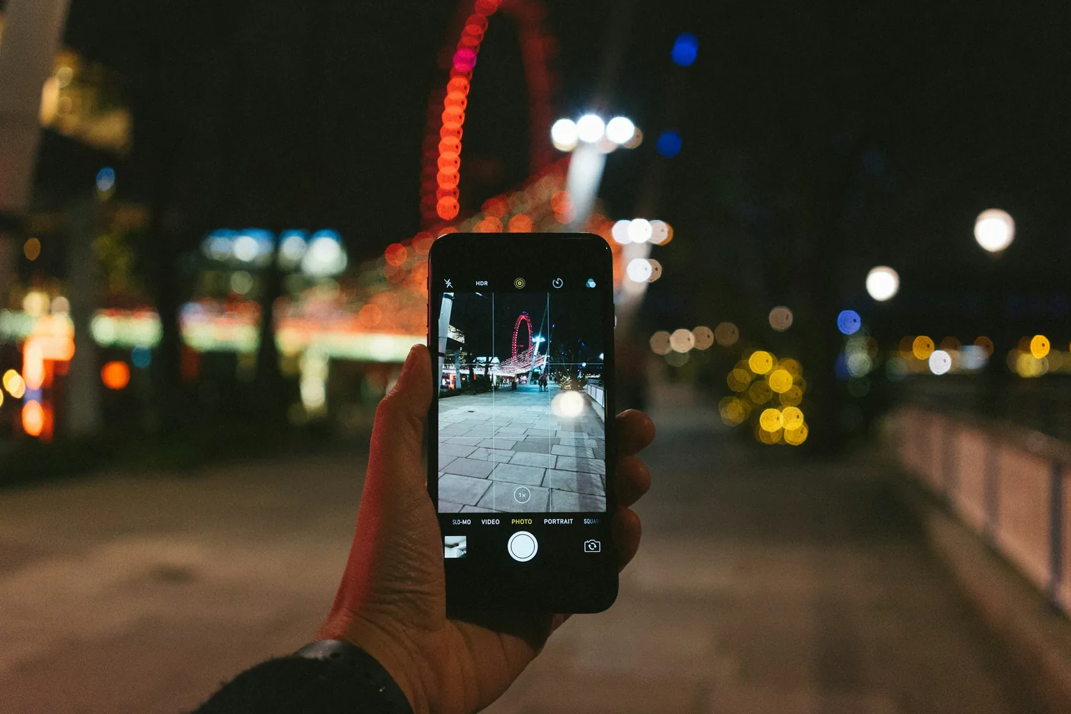 夜晚街頭手持手機拍照的畫面