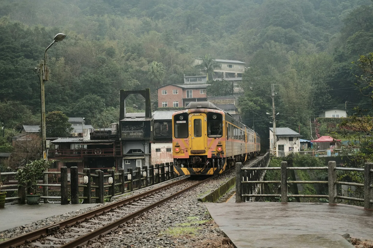 山邊小鎮旁駛過鐵橋的黃色區間車
